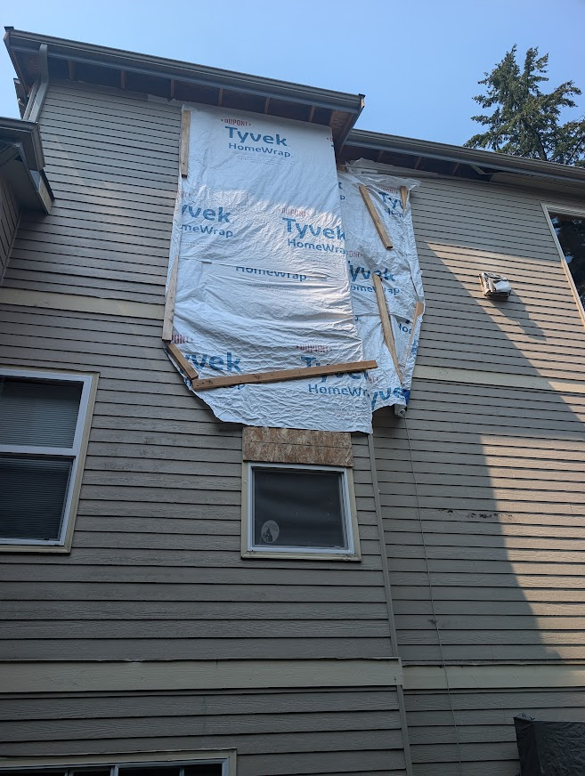 Side of a Sudden Valley home with house wrap covering storm damage from a fallen tree